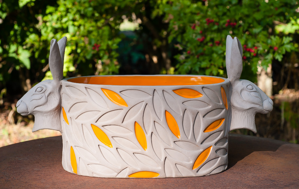 Oval kruka med orange mönster och harar.